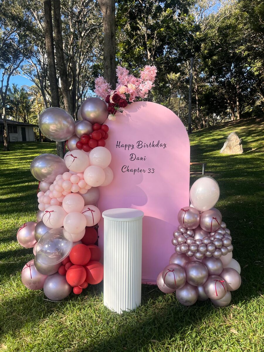 Birthday styling with pink backdrop, organic garland and chrome balloons